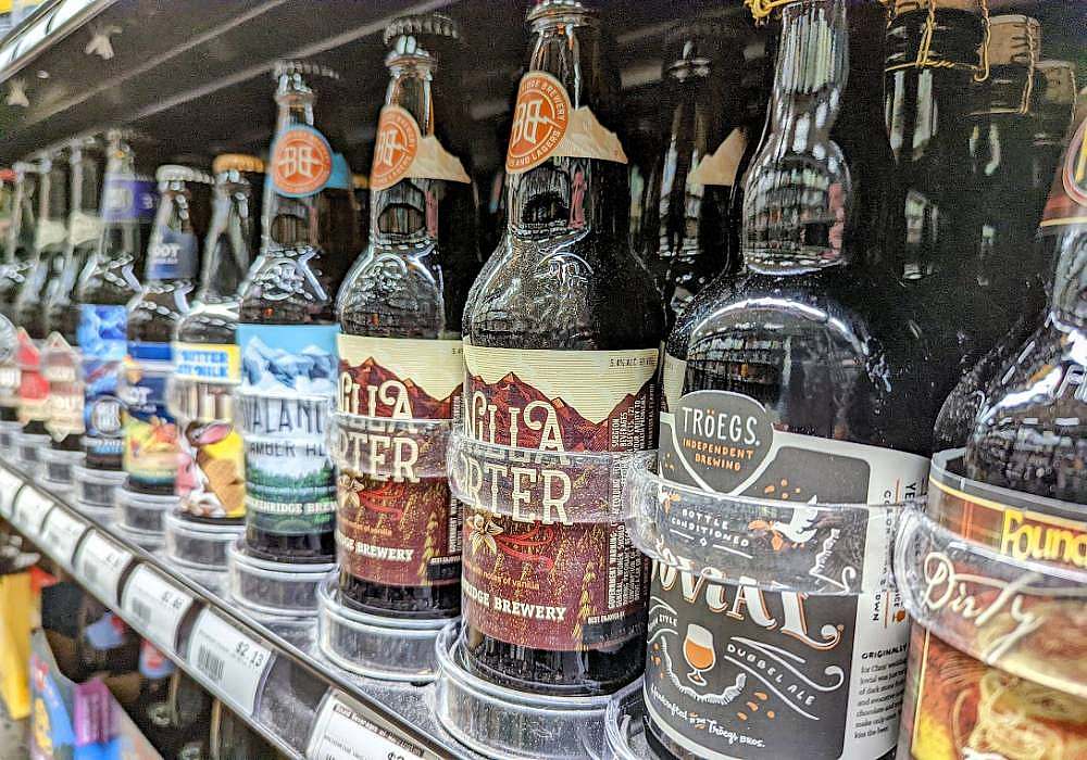 A row of beer bottles on a shelf in a grocery store.